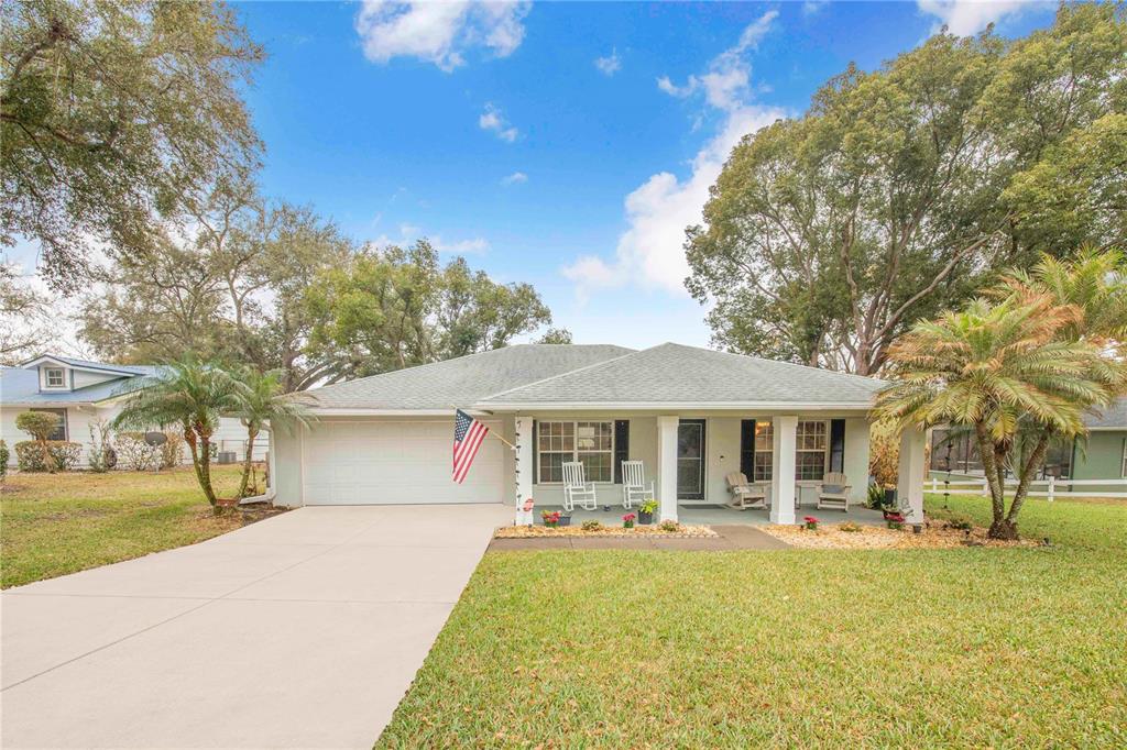 A single-story house with a light-colored exterior, a two-car garage, and a covered front porch — 194 S LAKE MARIAM DRIVE, WINTER HAVEN, FL