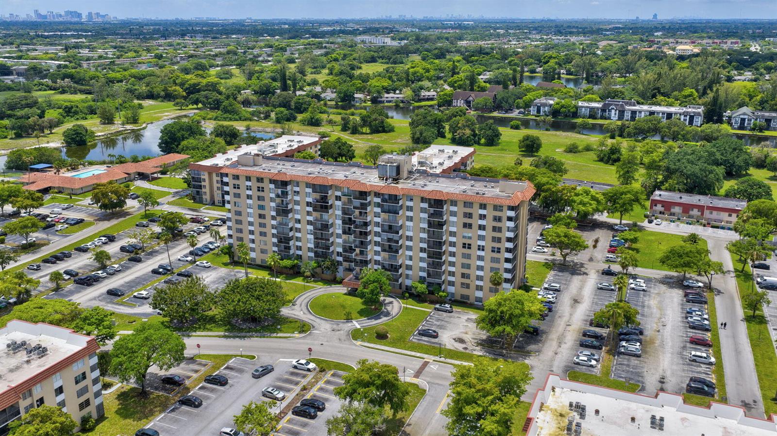 An aerial view shows a multi-story apartment building surrounded by parking lots and green space — 4174 Inverrary Drive # 513, Lauderhill FL 33319, LAUDERHILL, FL
