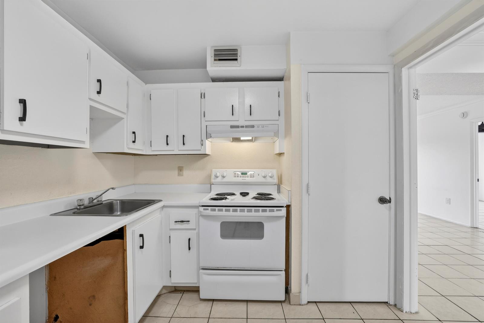 A small kitchen features white cabinets, a stainless steel sink, and a white electric stove — 4174 Inverrary Drive # 513, Lauderhill FL 33319, LAUDERHILL, FL