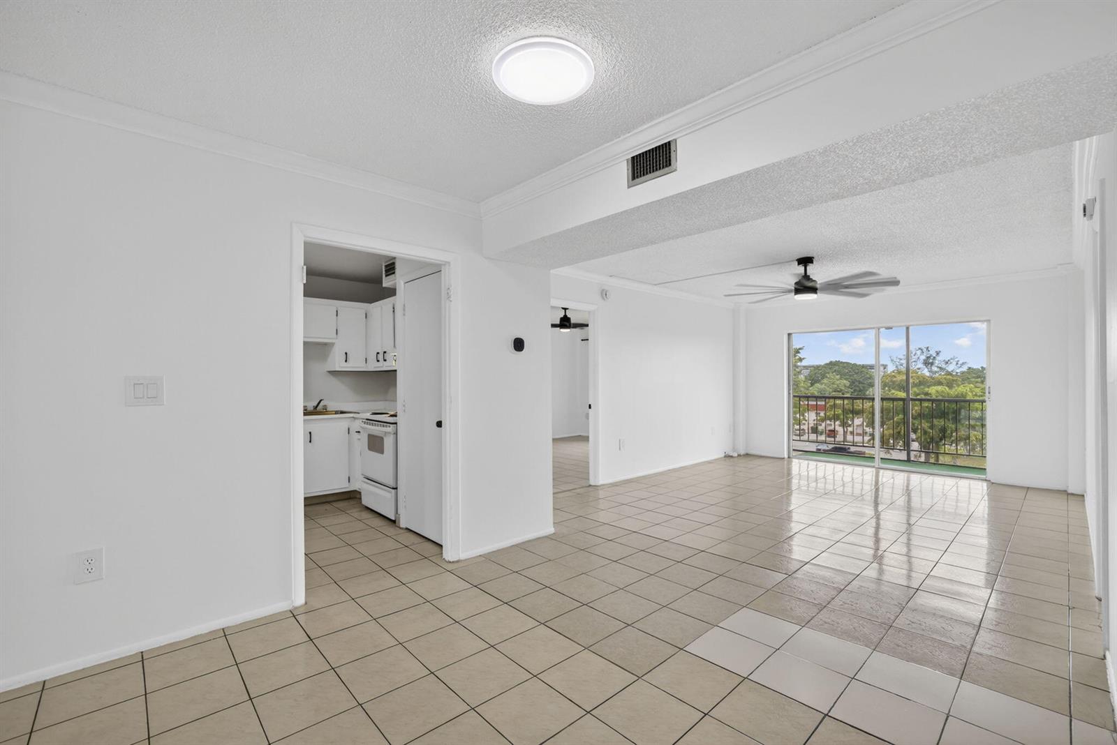 A tiled living area leads to a kitchen, a hallway, and a balcony with outdoor views — 4174 Inverrary Drive # 513, Lauderhill FL 33319, LAUDERHILL, FL