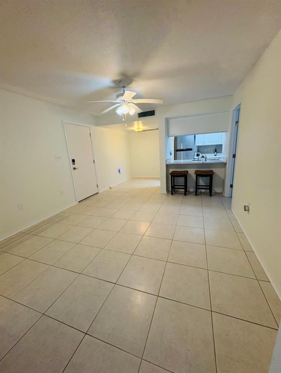 A room with light-colored tile flooring, a ceiling fan, and a kitchen breakfast bar — 5132 AMULET DRIVE UNIT 107, NEW PORT RICHEY, FL