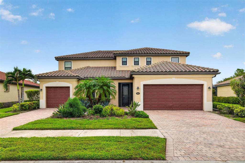 A two-story house with a tile roof, a three-car garage, and a paved driveway — 20630 GRANLAGO DRIVE, VENICE, FL