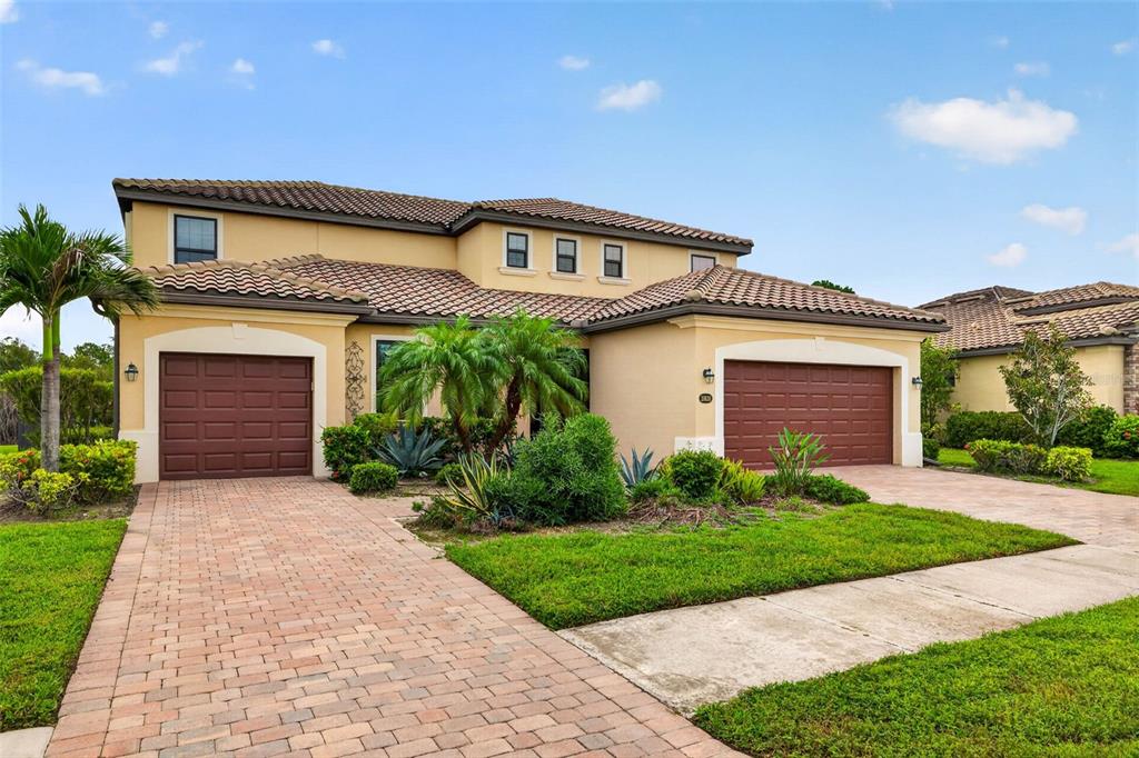 A two-story house with a tan exterior, two garage doors, and a paved driveway — 20630 GRANLAGO DRIVE, VENICE, FL