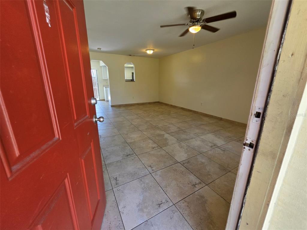 A view through an open red door into a living room with tiled flooring — 7450 WYNNEWOOD SQUARE UNIT 189, WINTER PARK, FL