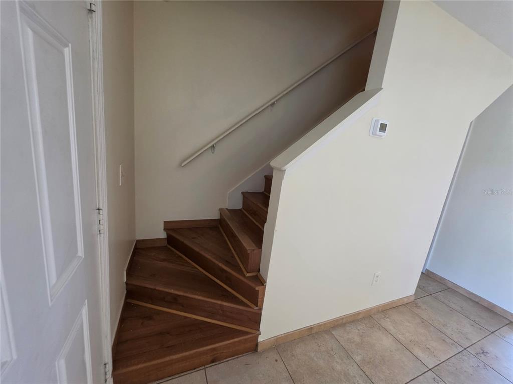 A staircase with wood-look treads and a white handrail leads upward from a tiled floor — 7450 WYNNEWOOD SQUARE UNIT 189, WINTER PARK, FL