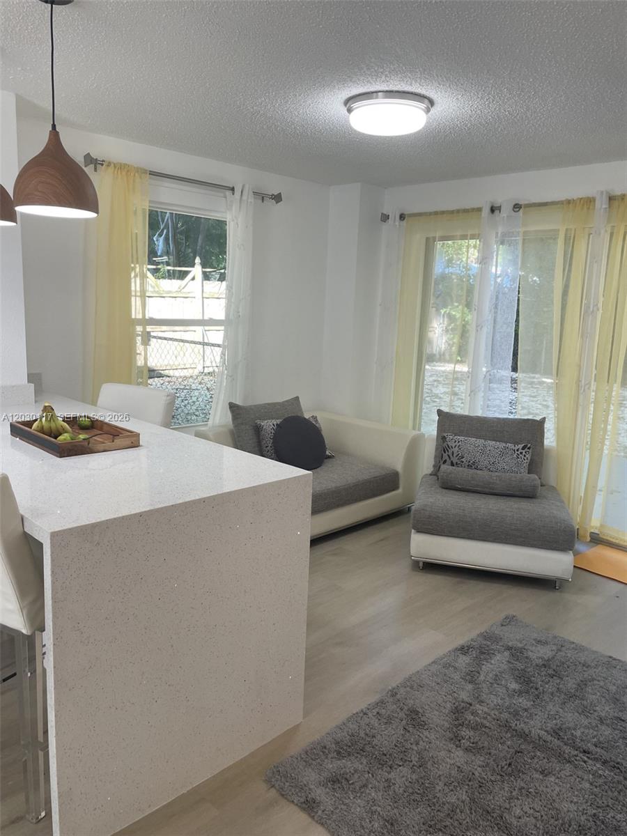 A kitchen island with a white countertop sits in a room with gray seating — 710 Barcelona Rd, Key Largo FL 33037, KEY LARGO, FL