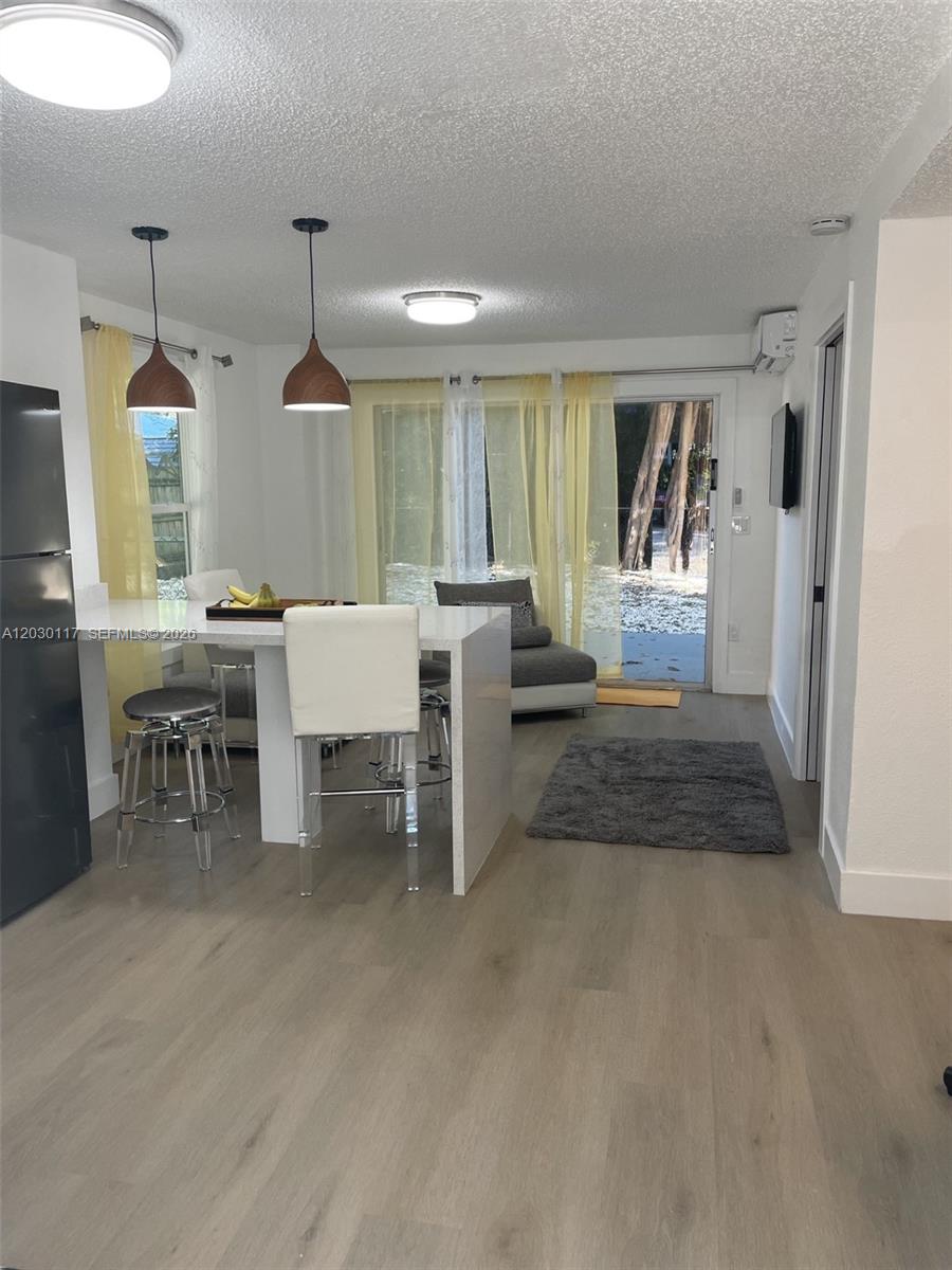 A kitchen and living area features a white island, bar stools, and yellow curtains — 710 Barcelona Rd, Key Largo FL 33037, KEY LARGO, FL