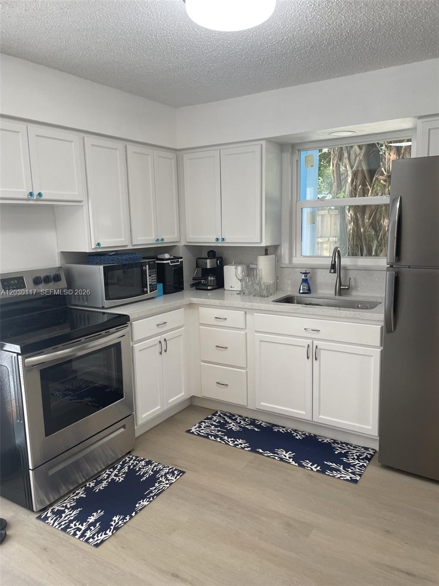 A kitchen features white cabinets, stainless steel appliances, light countertops, and patterned floor mats — 710 Barcelona Rd, Key Largo FL 33037, KEY LARGO, FL