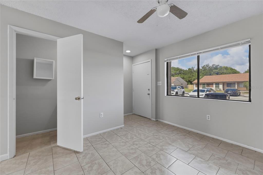 An empty room features light gray walls, tile flooring, a ceiling fan, and a window — 4799 SISSON ROAD, TITUSVILLE, FL