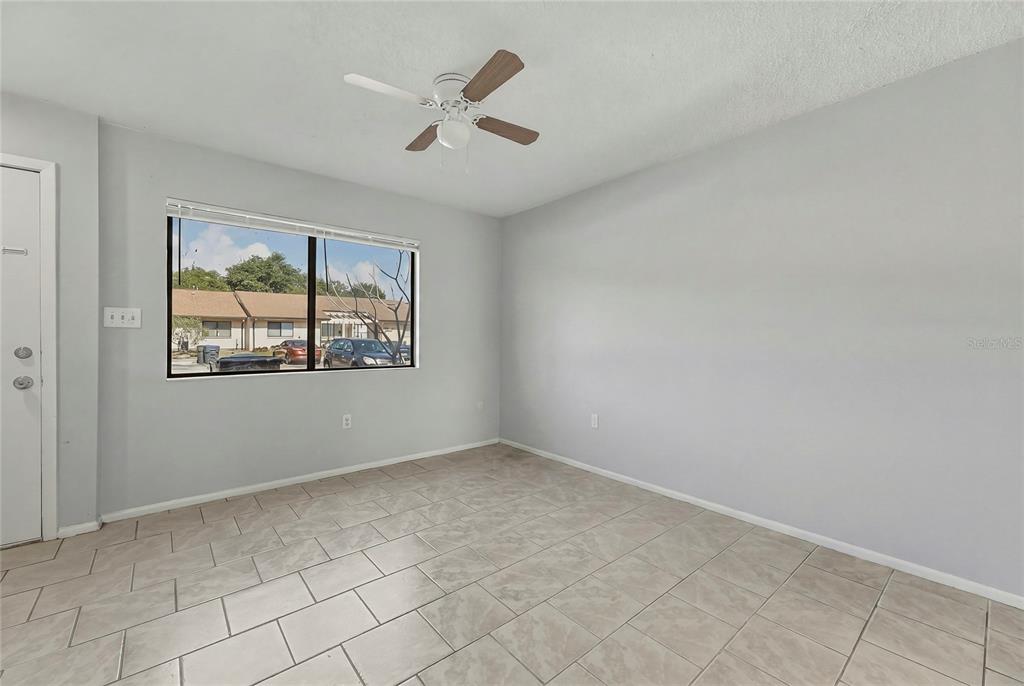 An empty room with light gray walls, tile flooring, a ceiling fan, and a large window — 4799 SISSON ROAD, TITUSVILLE, FL