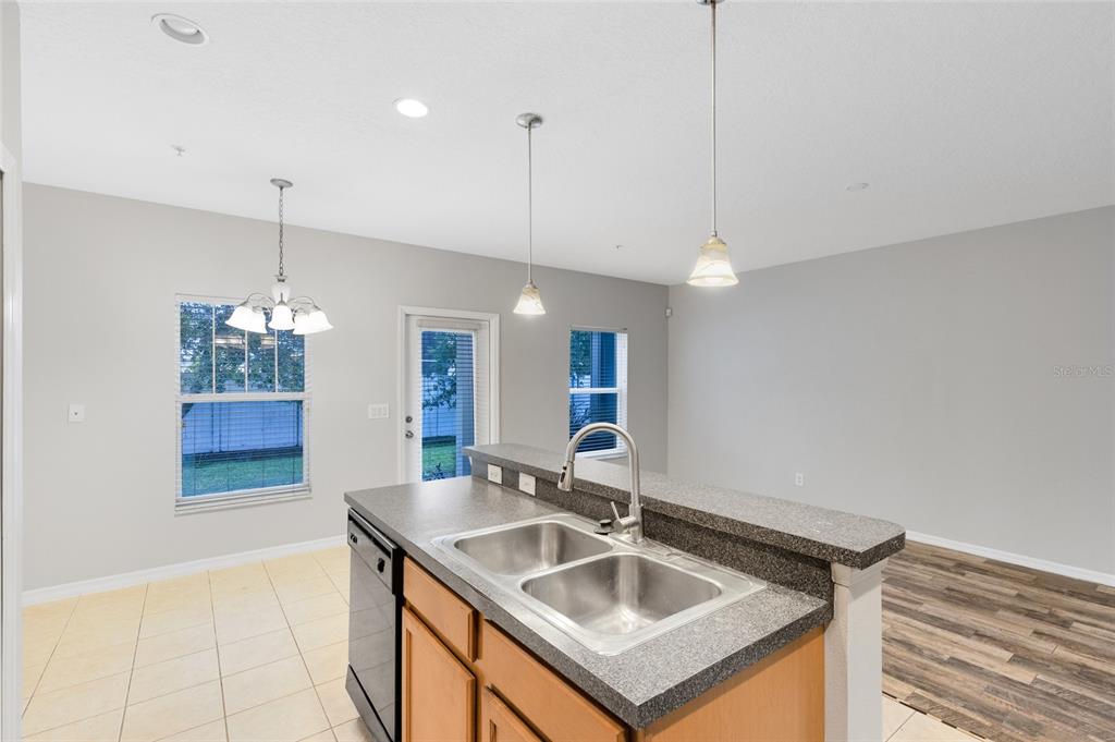 A kitchen island with a double sink faces a dining area with tile flooring — 2064 CYPRESS BAY BOULEVARD, KISSIMMEE, FL