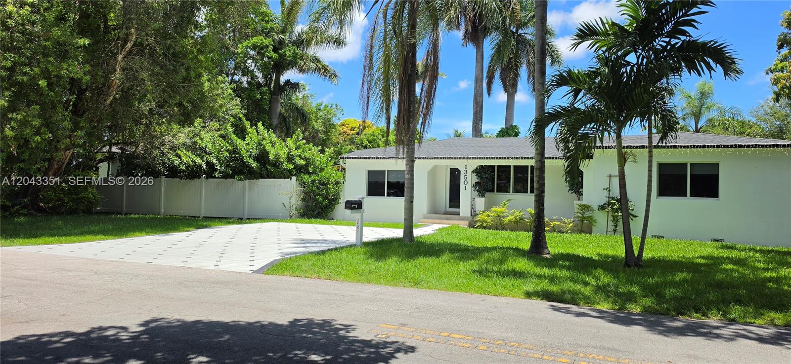 A single-story white house features a paved driveway, a green lawn, and tall palm trees — 13501 NE Miami Ct, Miami FL 33161, MIAMI, FL