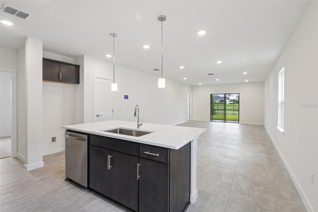 A kitchen island with a stainless steel sink and dishwasher faces an open living area — 3346 CUP DRIVE, LAKELAND, FL