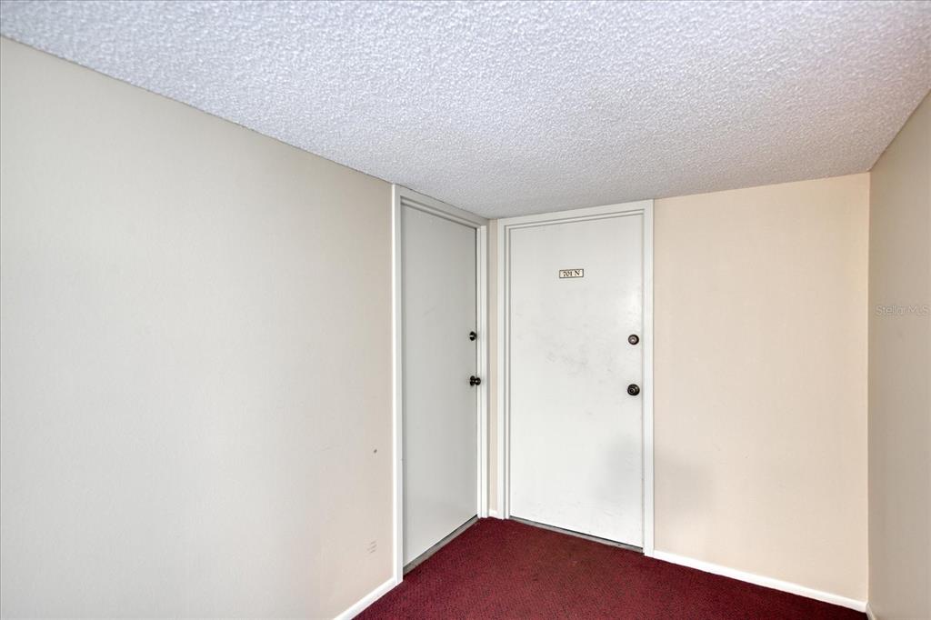 An interior view shows two white doors and red carpeting in a plain room — 440 S GULFVIEW BOULEVARD UNIT 701, CLEARWATER BEACH, FL