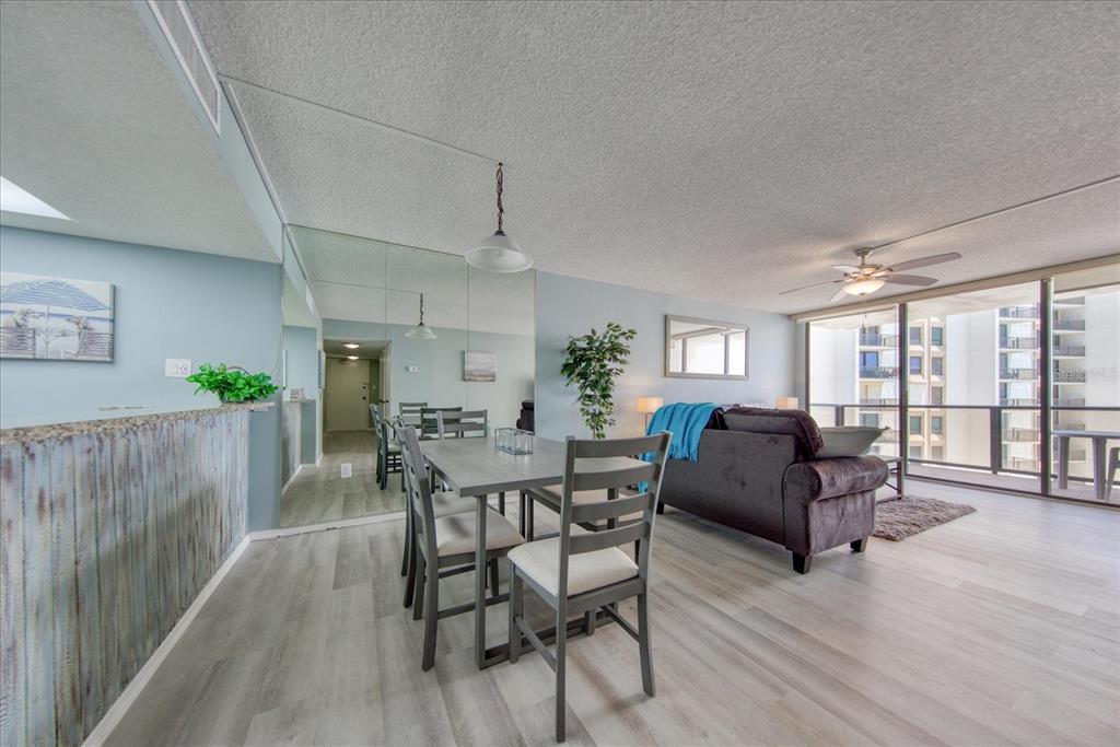 A dining area with a gray table and chairs sits next to a living room — 440 S GULFVIEW BOULEVARD UNIT 701, CLEARWATER BEACH, FL