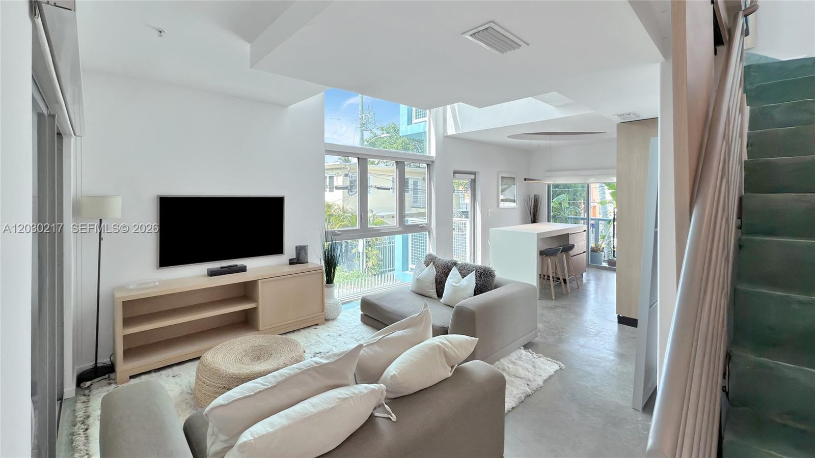 An outdoor balcony features a metal railing, potted plants, seating, and a gray door — 734 Michigan Ave, Miami Beach FL 33139, MIAMI BEACH, FL