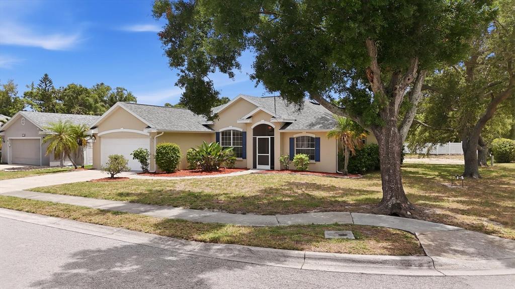 A single-story tan house with a two-car garage and a large tree in the yard — 2404 50TH DRIVE E, BRADENTON, FL