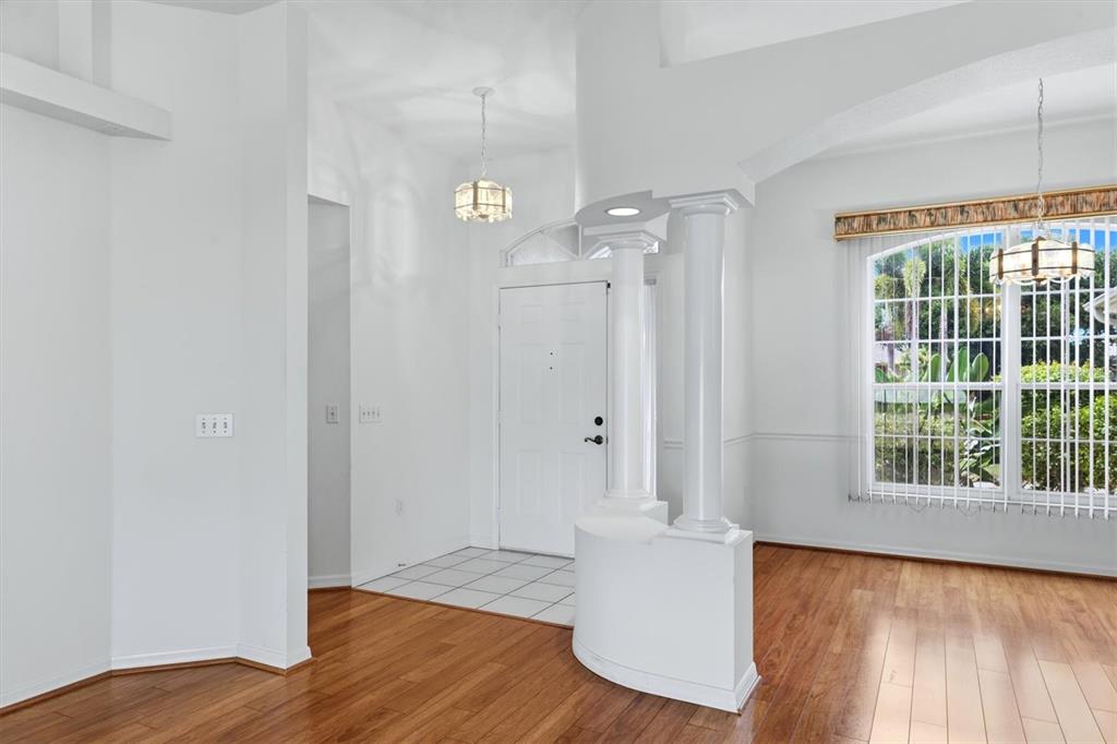 An open-concept living area features hardwood floors, a white column, and sliding glass patio doors — 2404 50TH DRIVE E, BRADENTON, FL