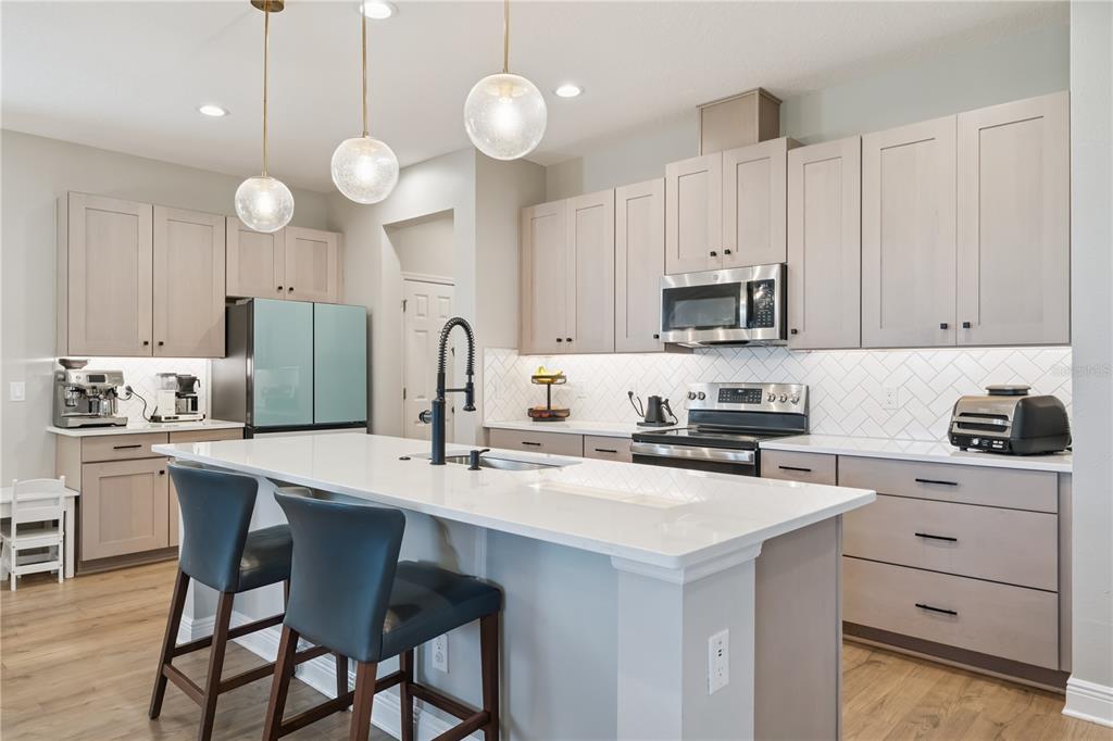 A modern kitchen features light wood cabinets, a white quartz island, and a herringbone backsplash — 14434 CRESTAVISTA AVENUE, CLERMONT, FL