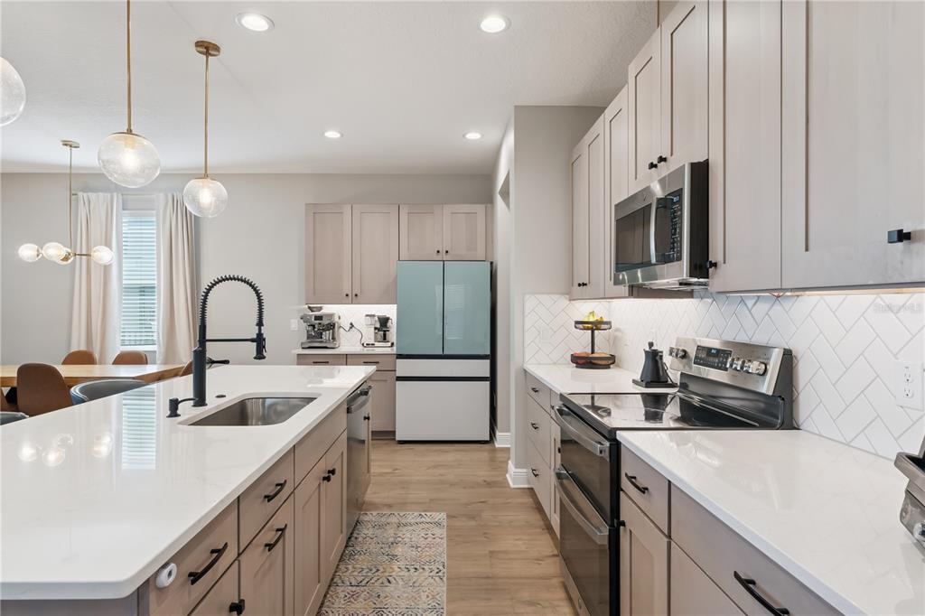 A modern kitchen features light wood cabinets, white countertops, a herringbone backsplash, and stainless appliances — 14434 CRESTAVISTA AVENUE, CLERMONT, FL