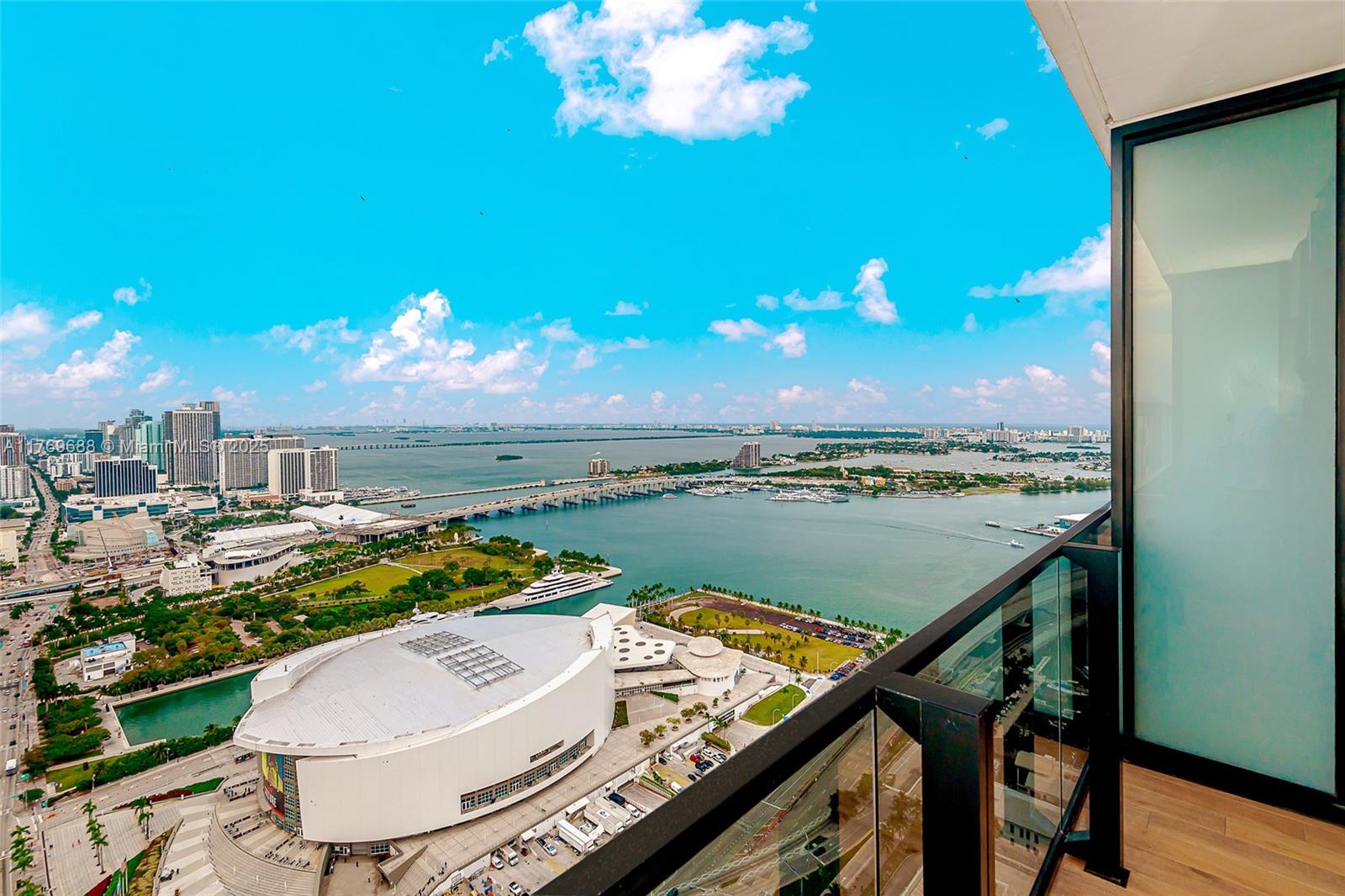 A high-rise balcony overlooks a large arena, a bridge, and a bay under a blue sky — 398 NE 5th St # 4008, Miami FL 33132, MIAMI, FL
