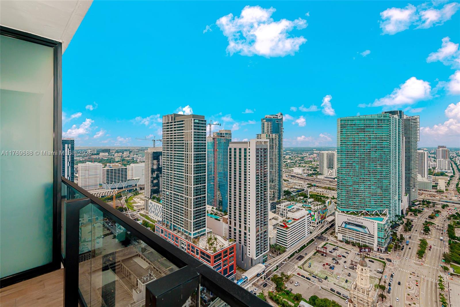 A high-angle view from a balcony overlooking a dense urban skyline with multiple skyscrapers — 398 NE 5th St # 4008, Miami FL 33132, MIAMI, FL