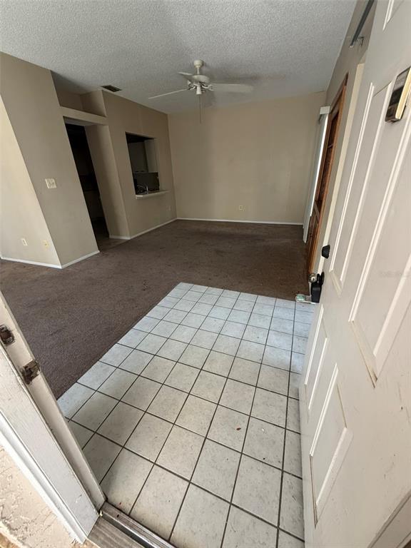 An entryway with tiled flooring leads into a carpeted living area with a ceiling fan — 47 EMERALD BAY DRIVE, OLDSMAR, FL