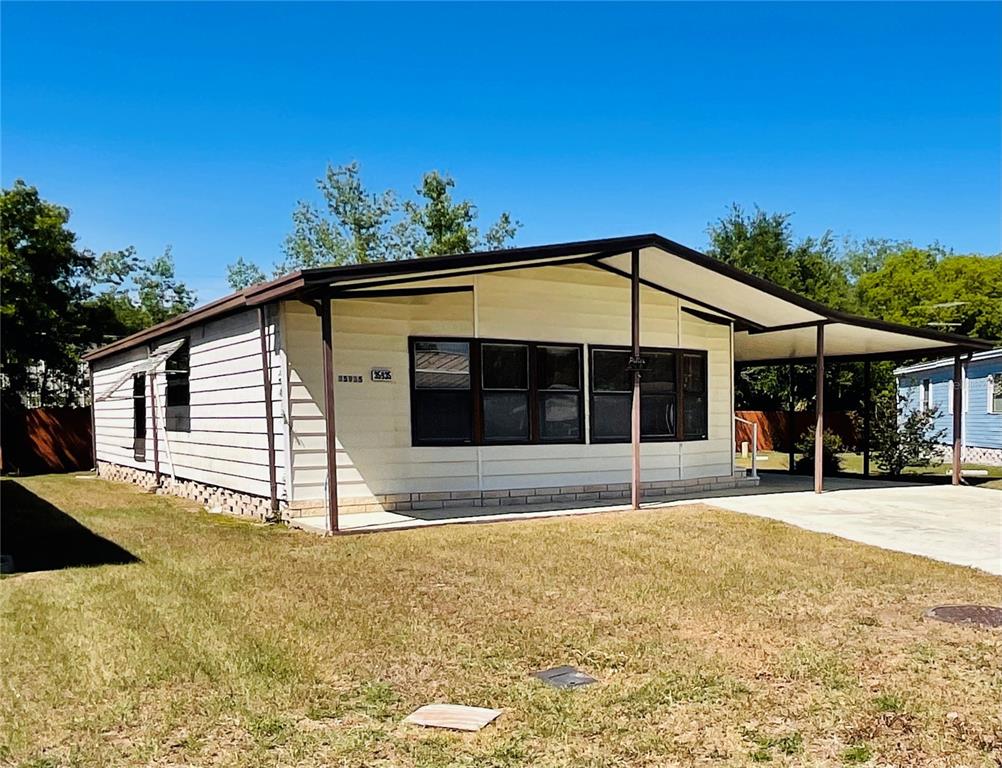 A single-story manufactured home with light siding, a carport, and a front lawn — 35935 TANDA CIRCLE, ZEPHYRHILLS, FL