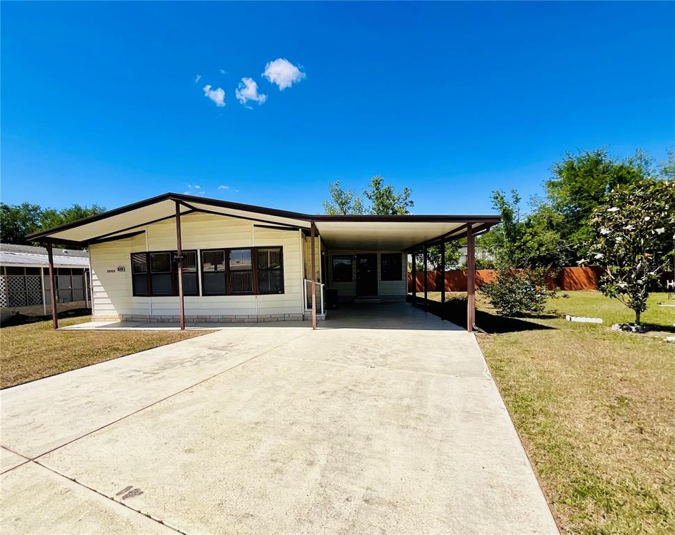 A single-story manufactured home with a concrete driveway and an attached carport — 35935 TANDA CIRCLE, ZEPHYRHILLS, FL