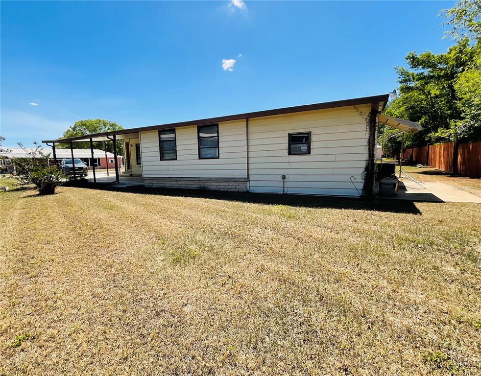 A side view of a single-story manufactured home with light siding and a metal carport — 35935 TANDA CIRCLE, ZEPHYRHILLS, FL
