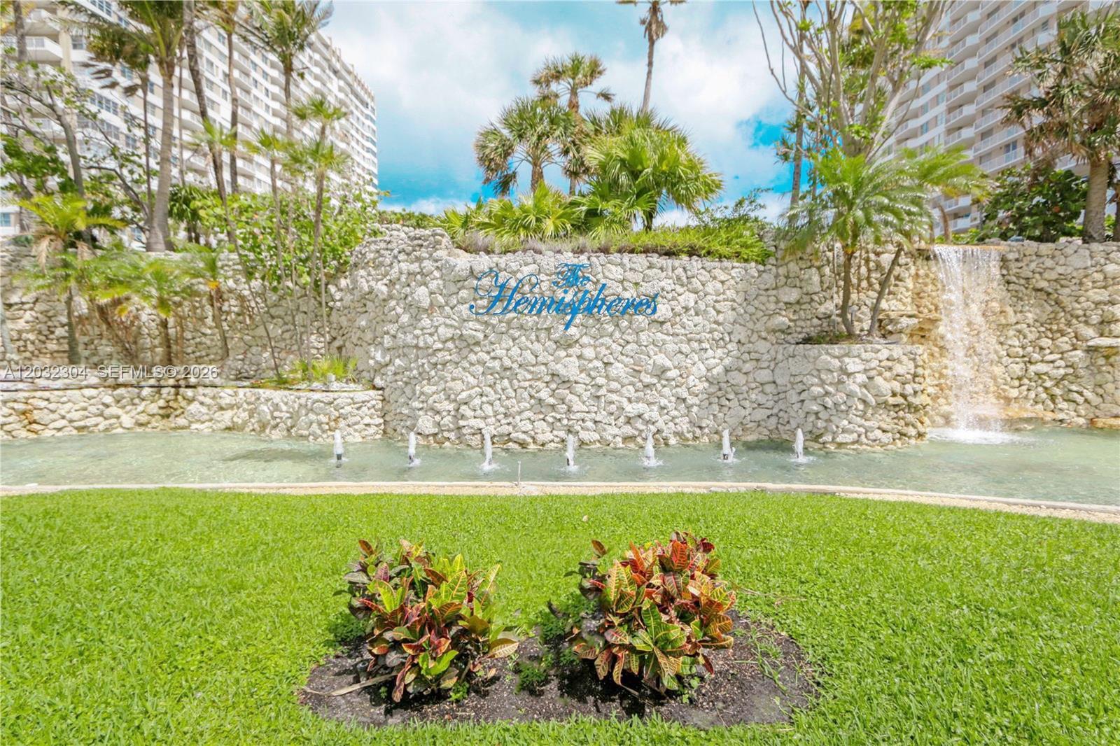 A stone wall with a waterfall and fountain sits behind a lawn with two shrubs — 1950 S Ocean Dr # 3D, Hallandale Beach FL 33009, HALLANDALE BEACH, FL