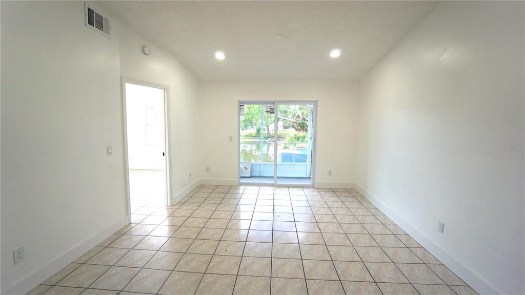 A room with light-colored tile flooring, white walls, recessed lighting, and a sliding glass door — 834 ANGELA LANE, KISSIMMEE, FL