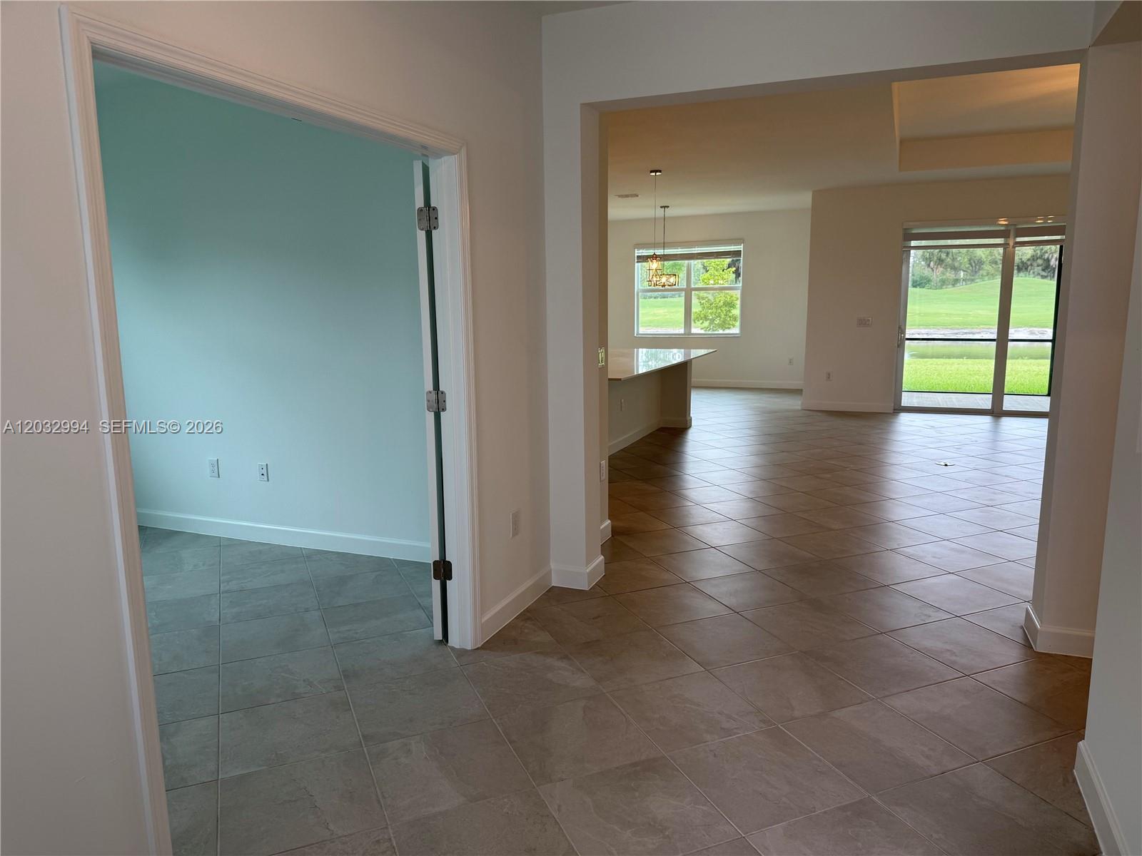 A tiled entryway leads to a room with light blue walls and an open-concept kitchen — 20821 Copperhead, Lehigh Acres FL 33936, LEHIGH ACRES, FL