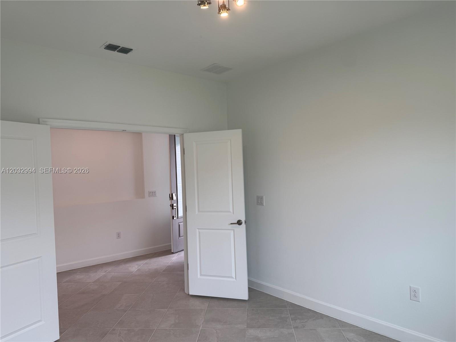 An interior room with light-colored walls, tile flooring, and an open white door — 20821 Copperhead, Lehigh Acres FL 33936, LEHIGH ACRES, FL
