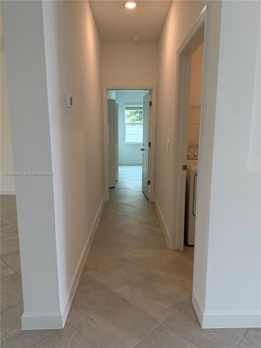 A hallway with tile flooring leads to a bedroom, with a laundry closet on the right — 20821 Copperhead, Lehigh Acres FL 33936, LEHIGH ACRES, FL