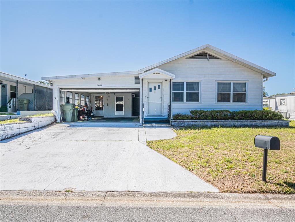 A single-story house with a white exterior, a carport, and a concrete driveway — 2609 HOUSTON PLACE, LEESBURG, FL