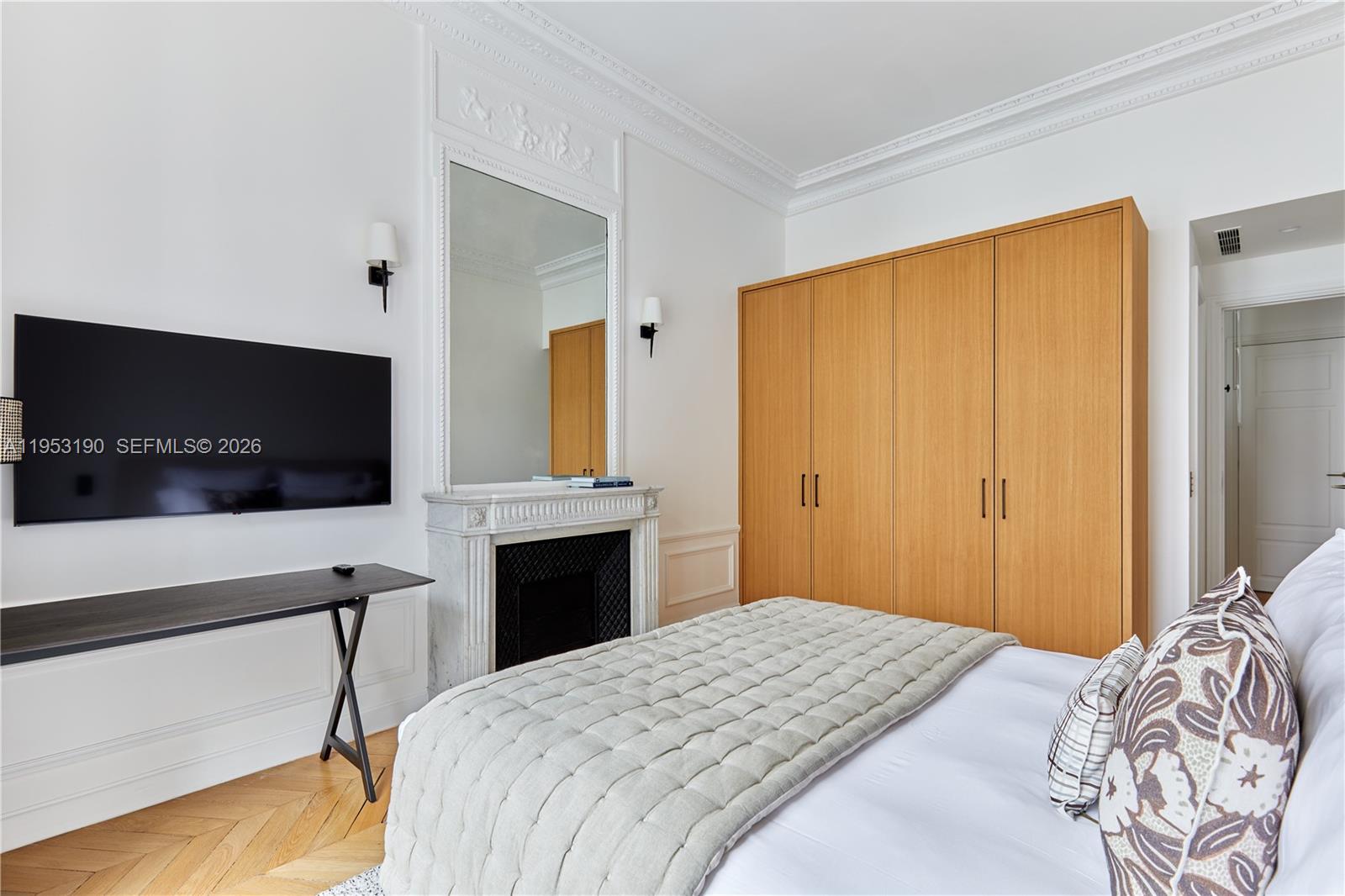A bedroom features a fireplace, a large mirror, wooden wardrobes, and a wall-mounted television — 11 Rue St Dominique # 403, FR, FR
