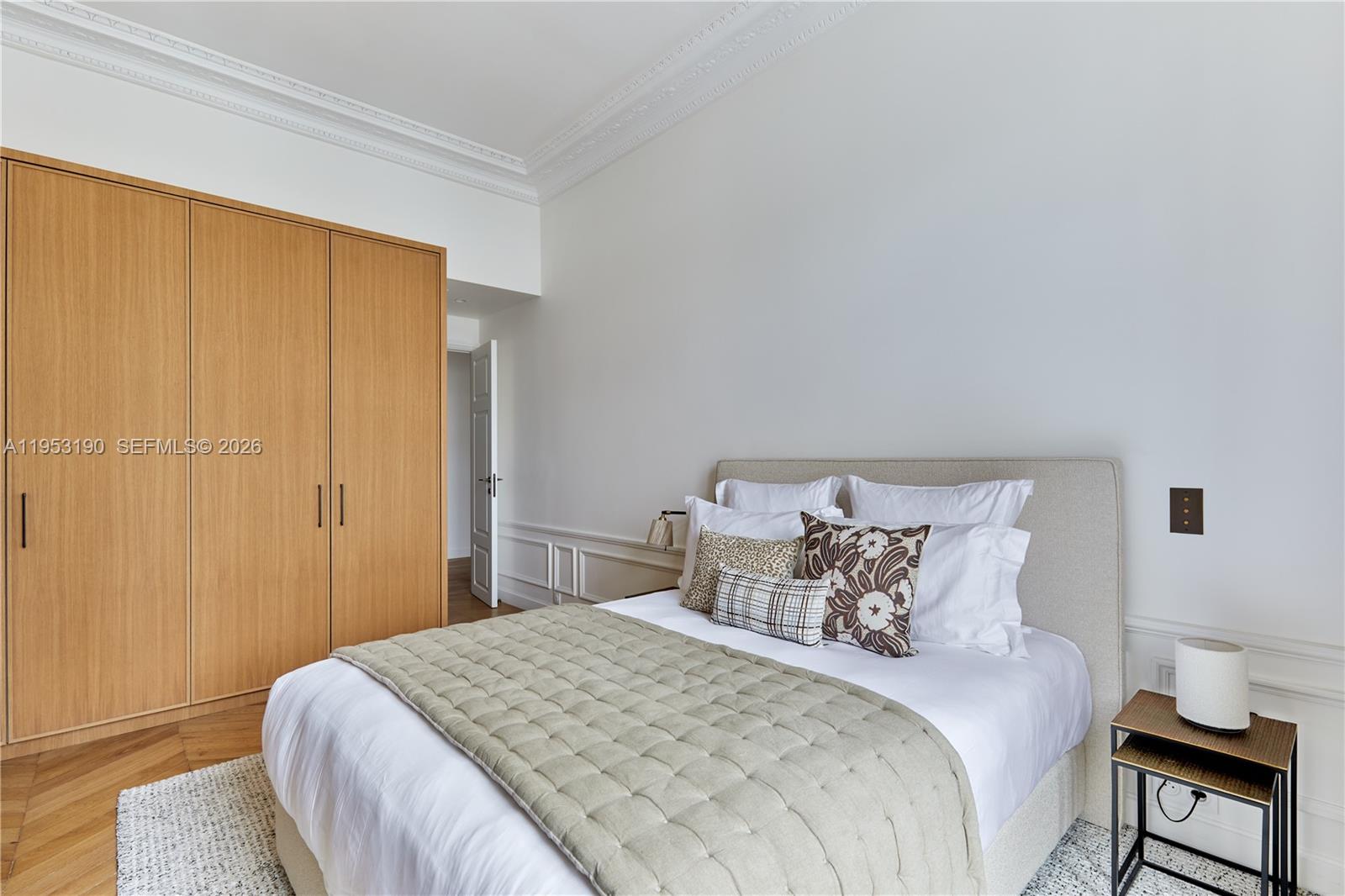A bedroom features a light wood wardrobe, a bed with decorative pillows, and white walls — 11 Rue St Dominique # 403, FR, FR