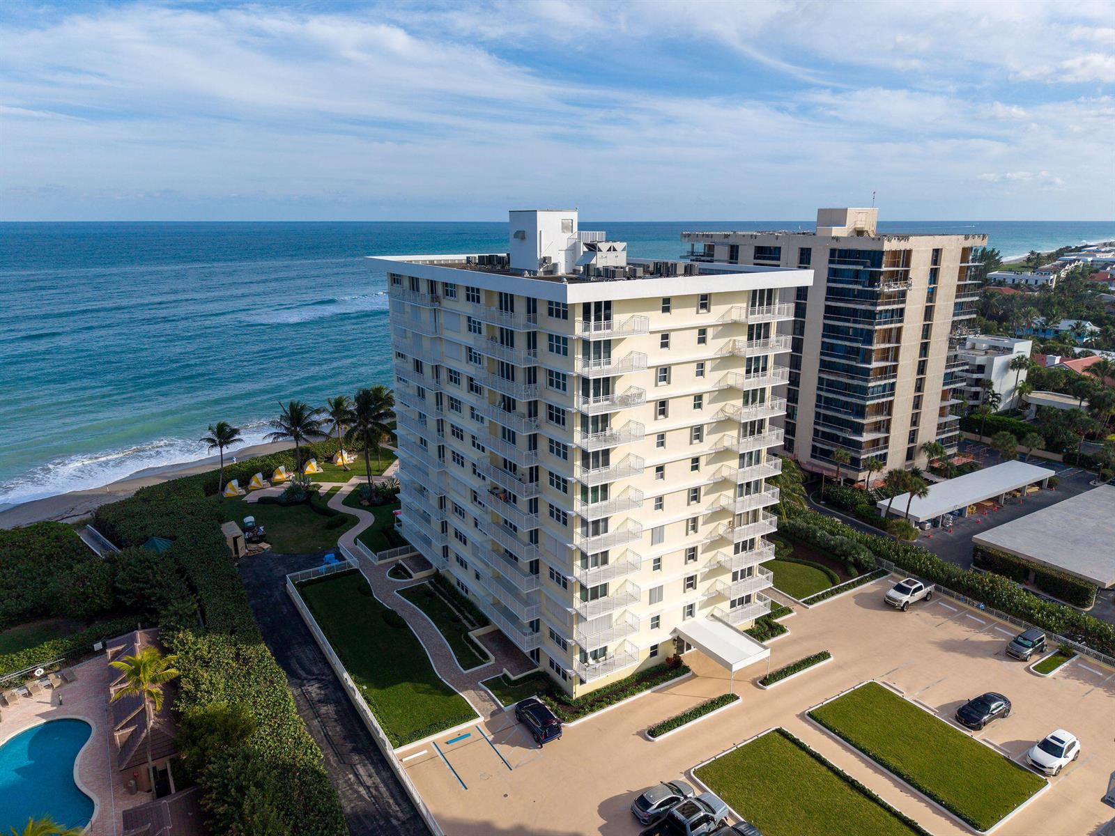 An aerial view shows a tall, light-colored apartment building situated next to the ocean — 500 Ocean Drive # 2d, Juno Beach FL 33408, JUNO BEACH, FL
