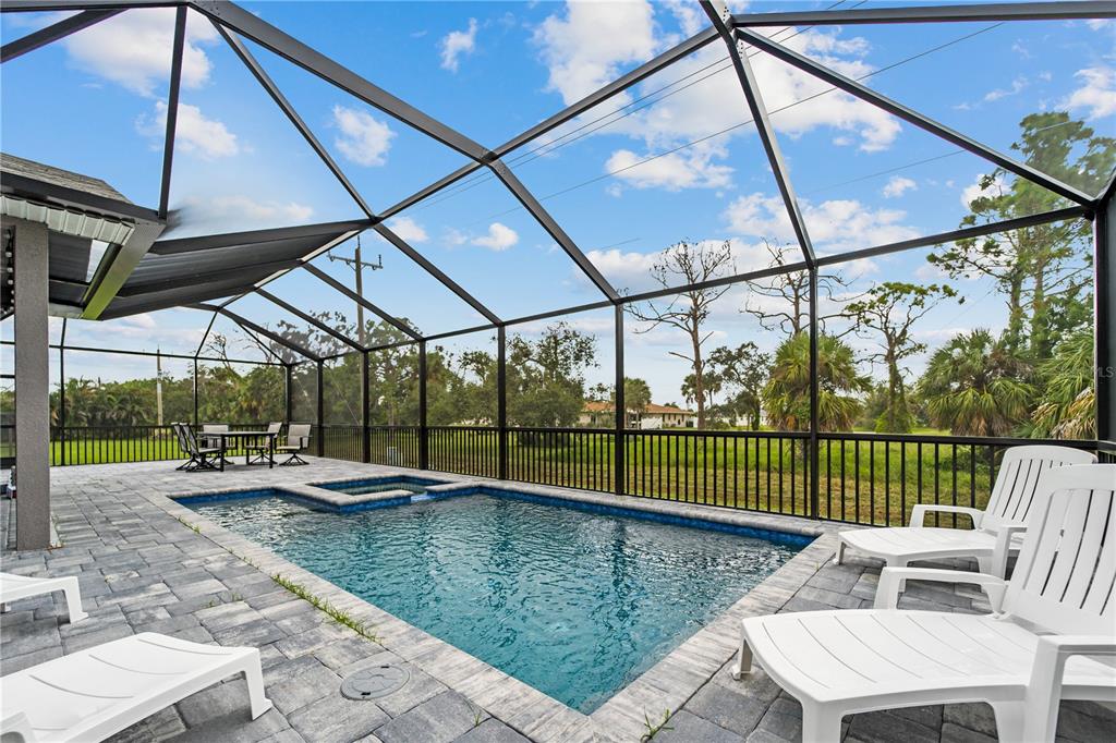 A screened-in pool patio features a rectangular pool, a spa, and white lounge chairs — 265 ANNAPOLIS LANE, ROTONDA WEST, FL