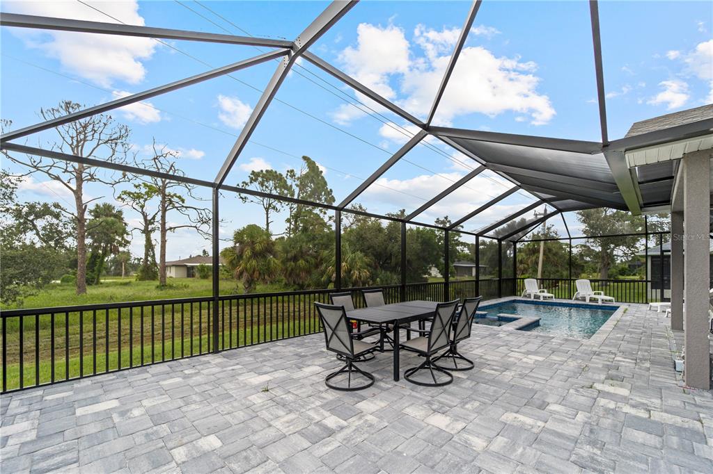 A screened-in patio features a dining set, a swimming pool, and paver flooring — 265 ANNAPOLIS LANE, ROTONDA WEST, FL
