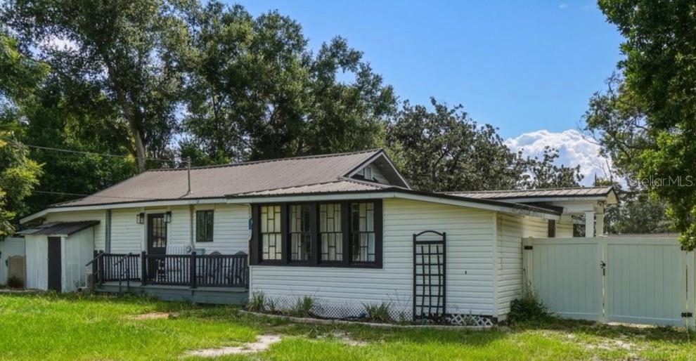 A white, single-story house with a metal roof, dark window frames, and a wooden porch — 650 9TH STREET NE, WINTER HAVEN, FL