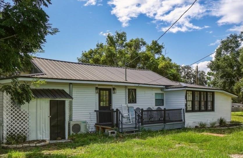 A white house with a metal roof, a wooden deck, and a small attached shed — 650 9TH STREET NE, WINTER HAVEN, FL