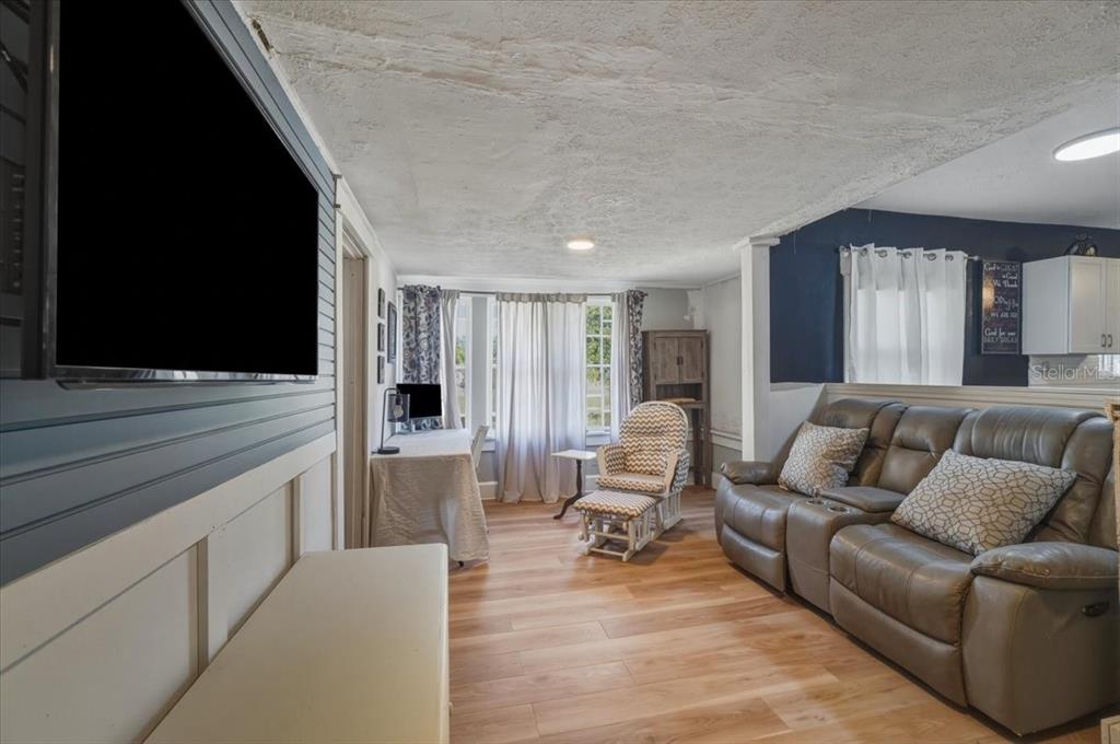 A living room features a grey leather sofa, a patterned rocking chair, and wood-look flooring — 650 9TH STREET NE, WINTER HAVEN, FL