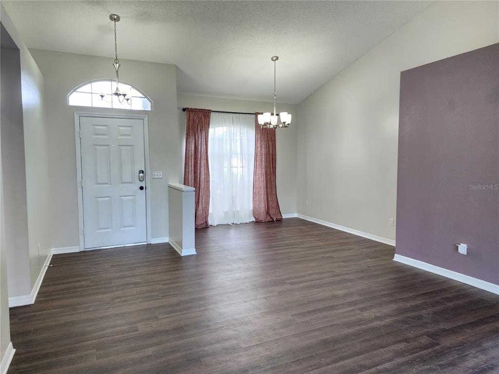 A room with dark wood-look flooring, a white front door, and a purple accent wall — 13404 IRONTON DRIVE, TAMPA, FL
