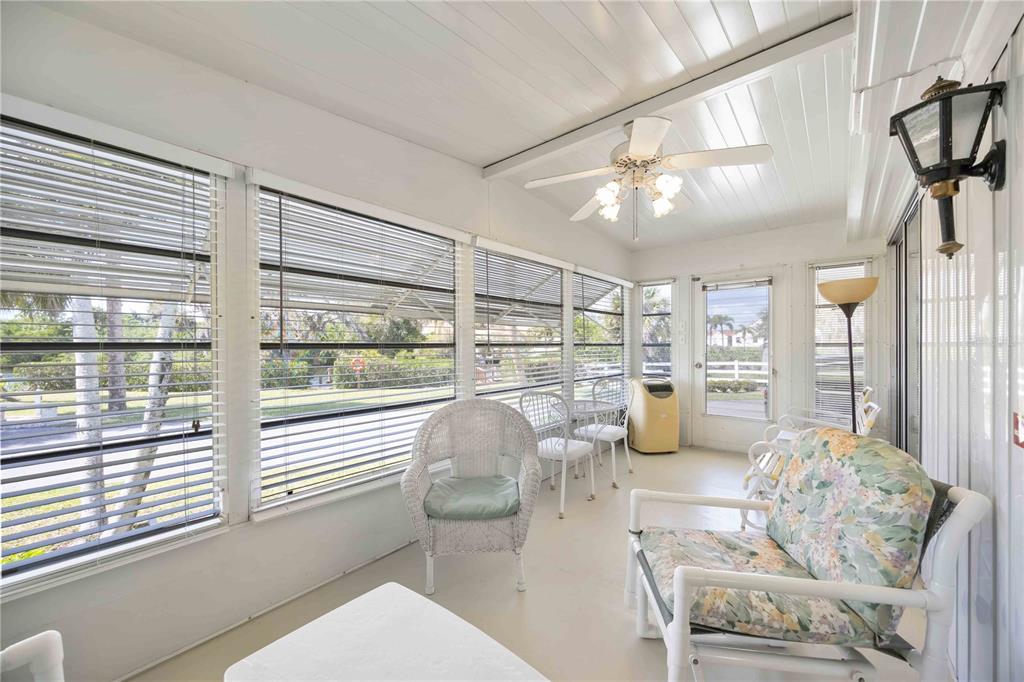 A sunroom features white walls, a ceiling fan, and large windows with horizontal blinds — 10303 BURNT STORE ROAD UNIT 221, PUNTA GORDA, FL