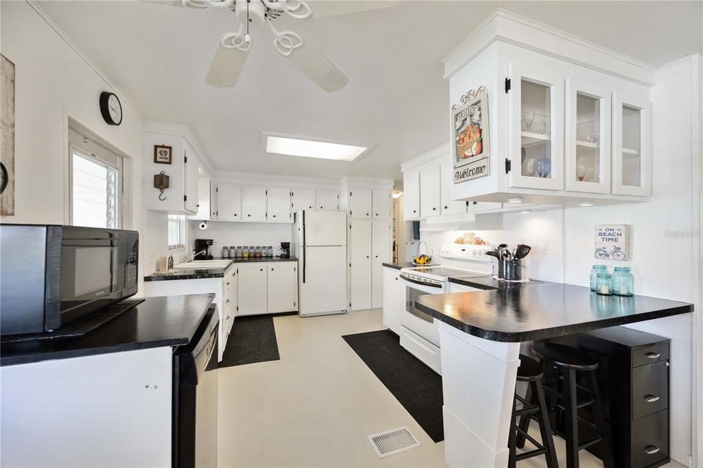 A kitchen features white cabinets, black countertops, a white refrigerator, and a breakfast bar — 10303 BURNT STORE ROAD UNIT 221, PUNTA GORDA, FL