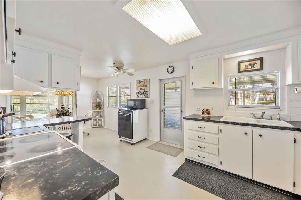 A kitchen features white cabinets, dark countertops, a breakfast bar, and a glass-paneled exterior door — 10303 BURNT STORE ROAD UNIT 221, PUNTA GORDA, FL