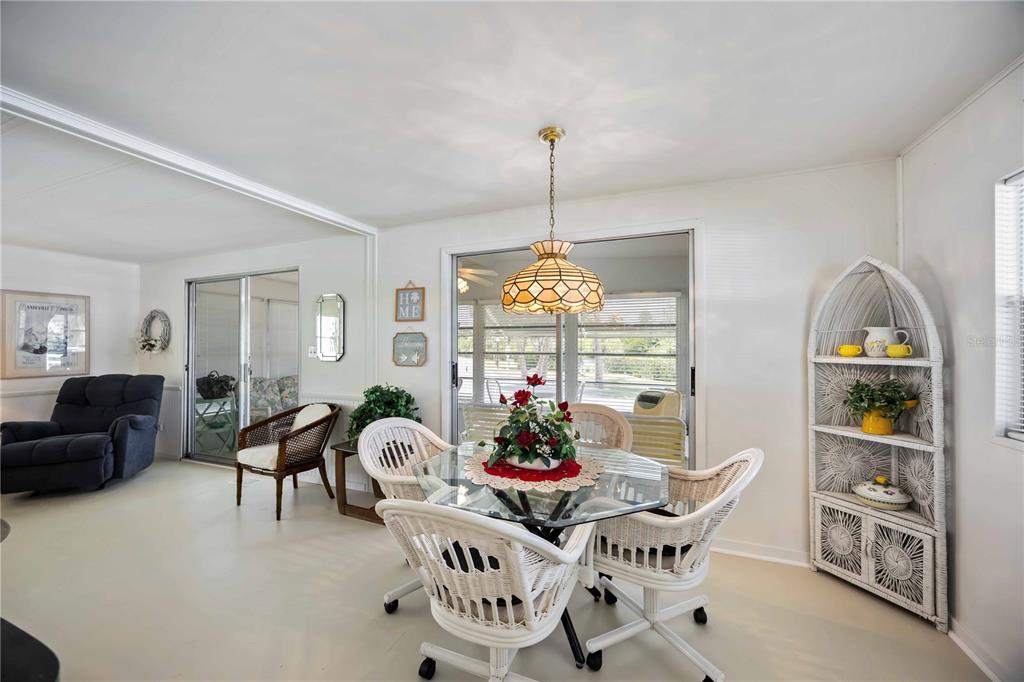 A dining area features a glass-topped table with white wicker chairs under a pendant light — 10303 BURNT STORE ROAD UNIT 221, PUNTA GORDA, FL
