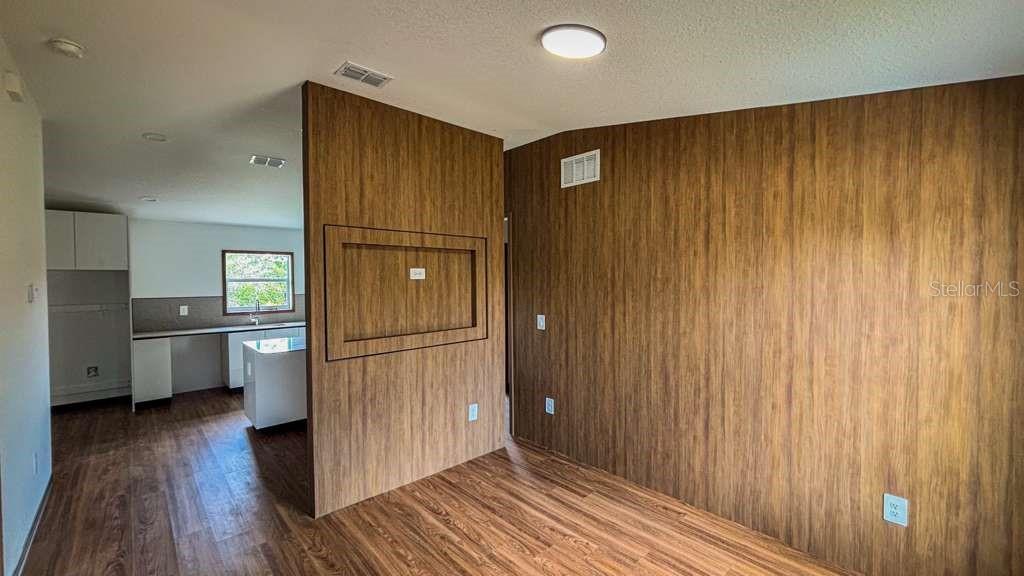 A room with wood-paneled walls and flooring features a recessed wall cutout for a television — 5620 VIRTUDES STREET, SEBRING, FL